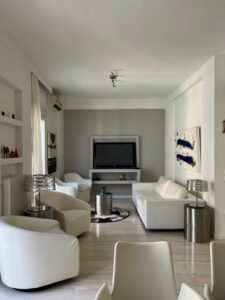 Sleek contemporary living room with white armchairs, sofa, and abstract art.