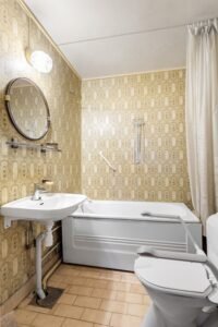 Cozy vintage bathroom interior featuring a bathtub, mirror, and elegant wallpaper.