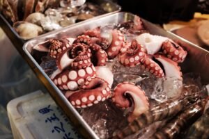 Close-up shot of raw octopus tentacles on ice displayed in a Tokyo seafood market, showcasing fresh seafood.
